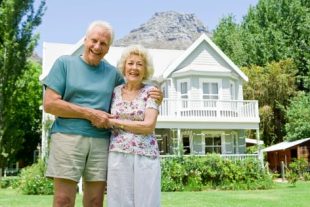 Portrait-of-smiling-senior-couple-by-house-89794602.jpg